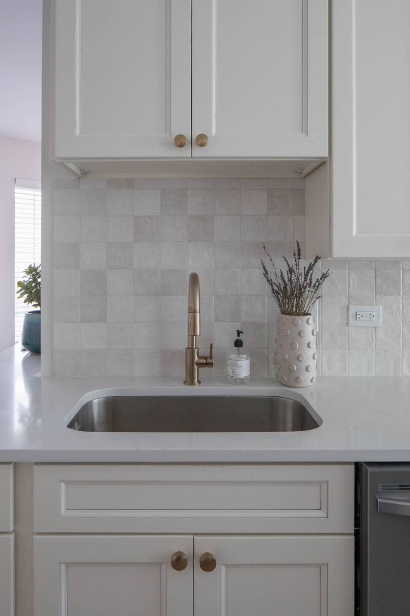 Kitchen sink with golden faucet and beige backsplash